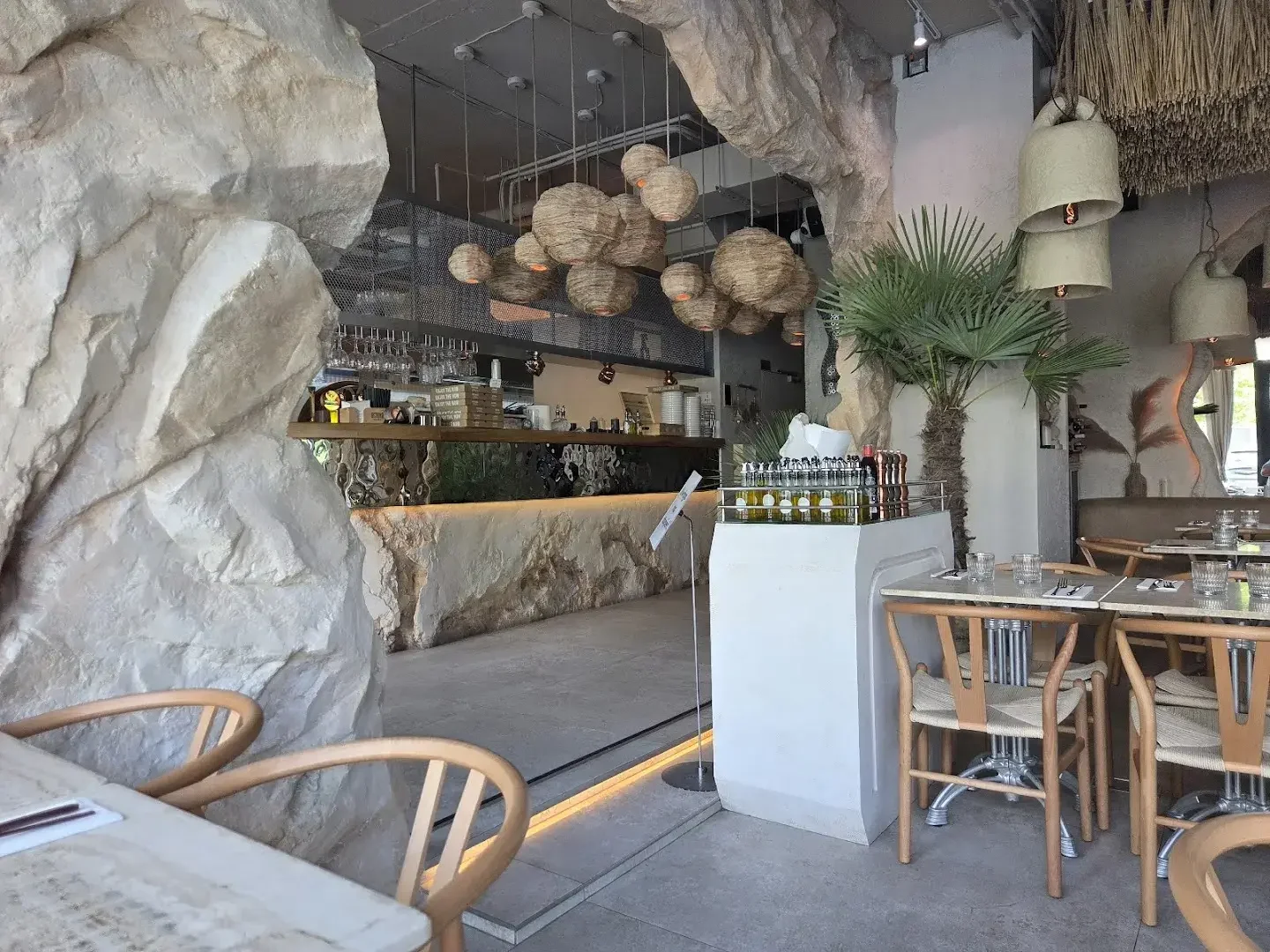 Surowa betonowa ściana, drewniana zabudowa i palma w sali restauracji