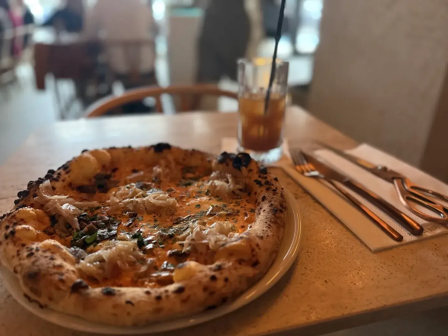 Pizza na drewnianej desce z mozzarellą i ziołami, kieliszek wina obok