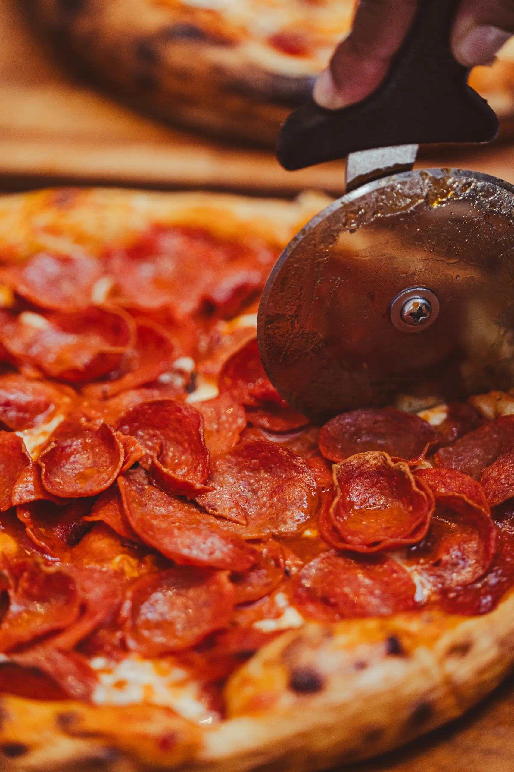 Krojenie pizzy pepperoni nożem na desce