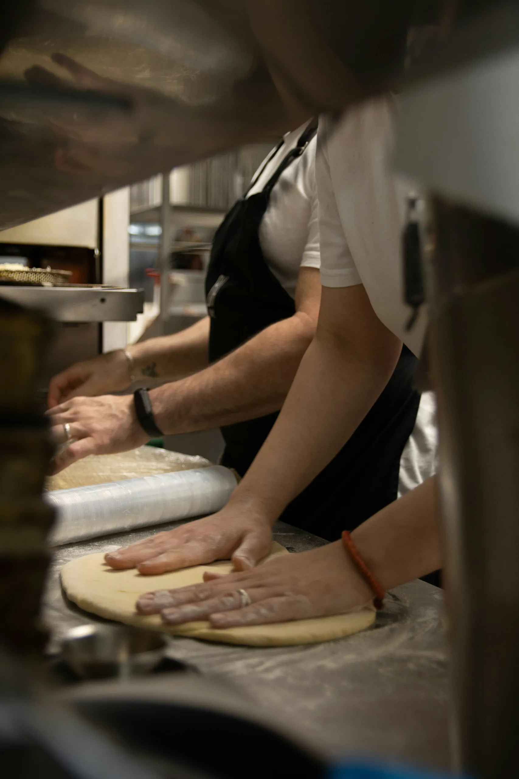 Ręce wyrabiające ciasto na pizzę przy blacie w kuchni