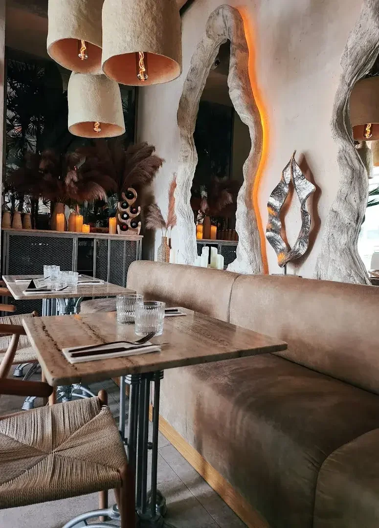 Sala restauracji: białe siedziska, marmurowe stoły, ciepłe lampy